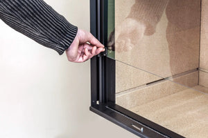 Fondis Stella 3 H1000 glass gliding door halfway closed held by a model's hand