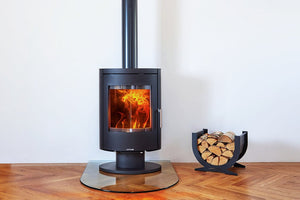 Opus Harmony Multi-fuel Stove on a glass hearth with flames and next to log storage