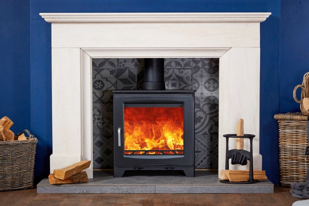 Woodford - Didsbury 5kW Wide Multi-fuel Stove with flames in a white fireplace suite on a blue wall